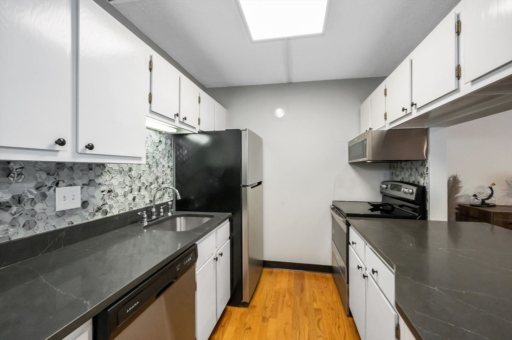 159 Main Street, Unit 15B Stoneham, MA 02176 - Photo 3 of 25 a kitchen with stainless steel appliances a sink a stove and a refrigerator