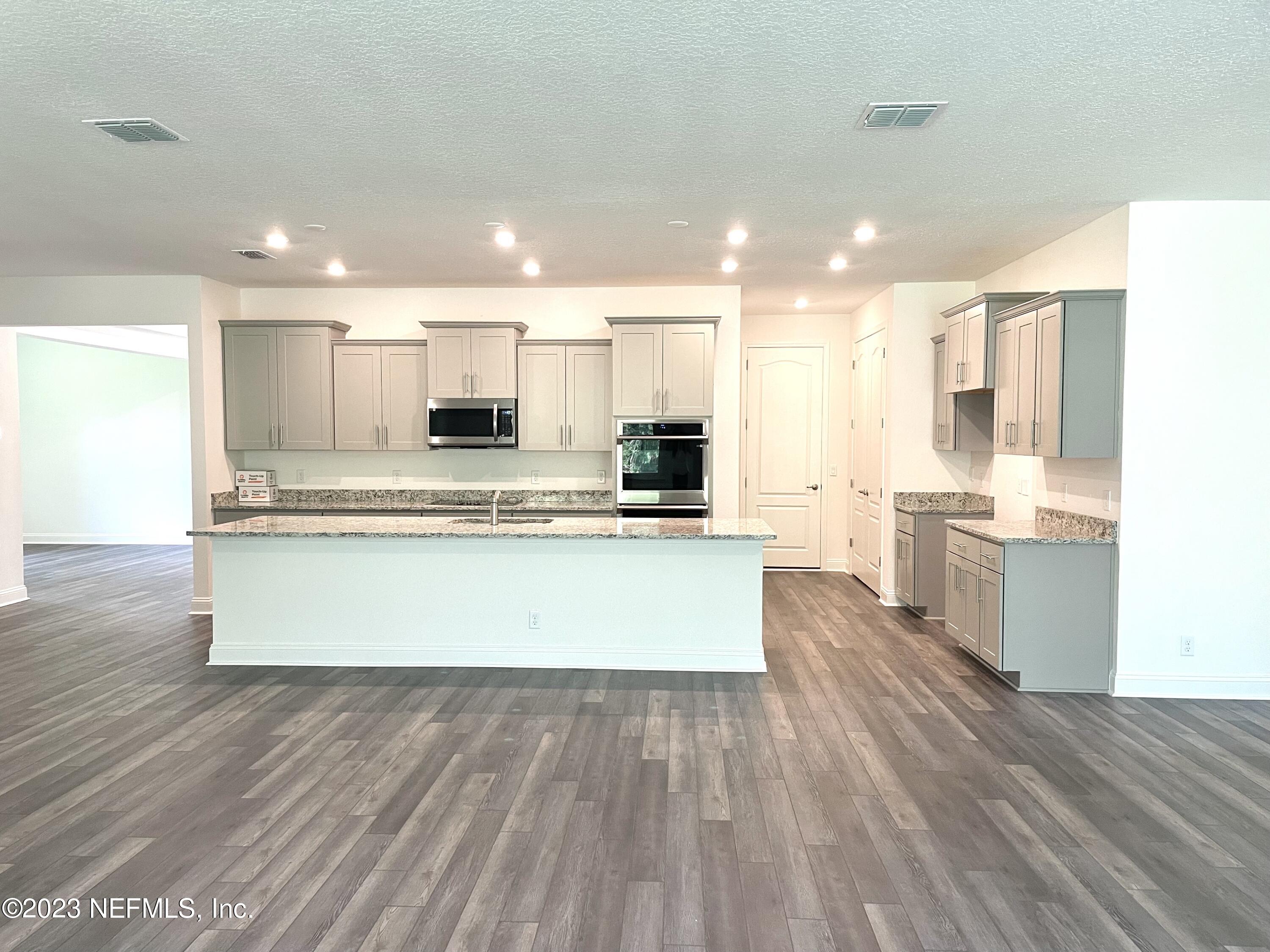 1515 Lake Foxmeadow Road Middleburg, FL 32068 - Photo 8 of 22 a large kitchen with kitchen island a sink dishwasher stove and white cabinets with wooden floor