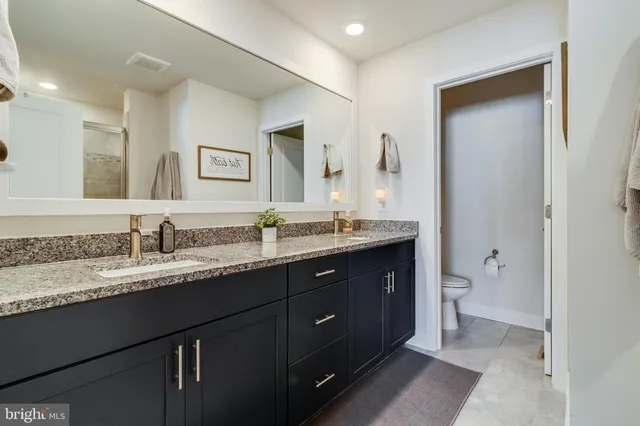 a bathroom with a granite countertop sink double and mirror