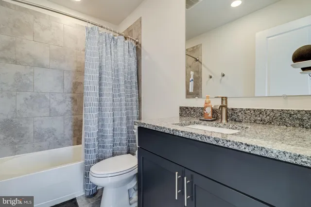 a bathroom with a granite countertop sink toilet and shower