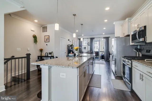 a kitchen with stainless steel appliances granite countertop a refrigerator a stove top oven a sink dishwasher and white cabinets with wooden floor