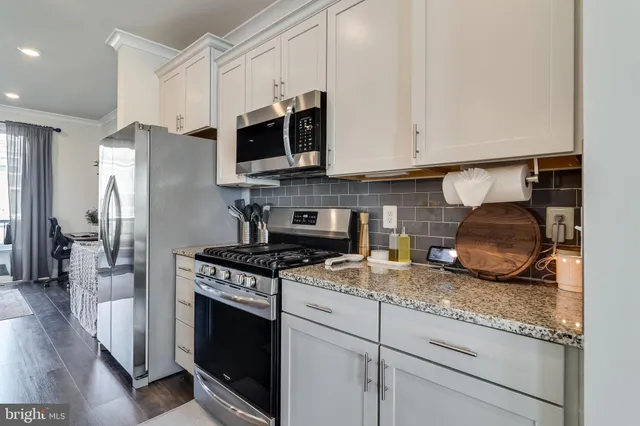 a kitchen with granite countertop white cabinets and stainless steel appliances