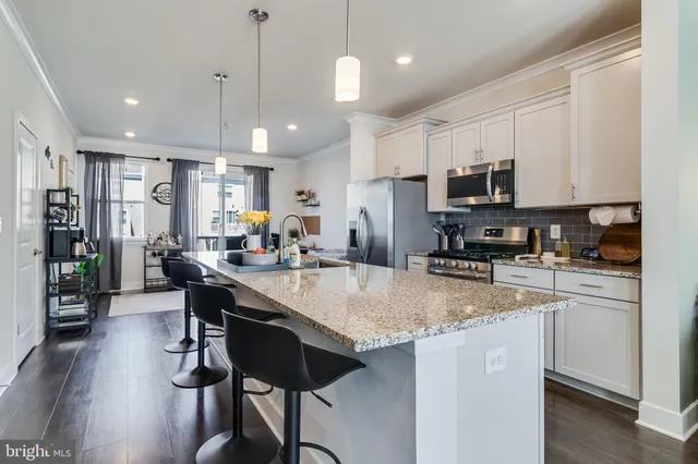 a kitchen with stainless steel appliances granite countertop a stove a refrigerator a kitchen island a sink a stove a dining table and chairs