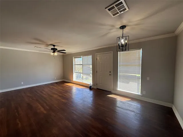 an empty room with wooden floor closet and windows