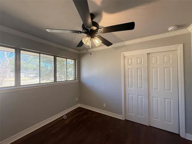 an empty room with wooden floor fan and windows