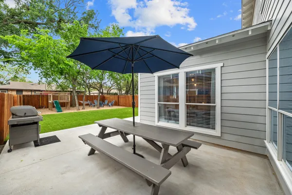 a view of a patio with table and chairs potted plants and large tree