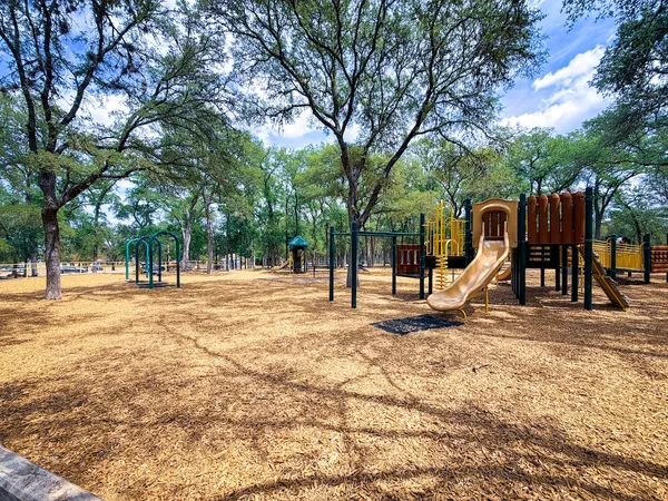 a view of a park with swings and a large tree