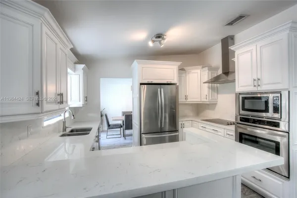a kitchen with stainless steel appliances a stove a sink and a refrigerator