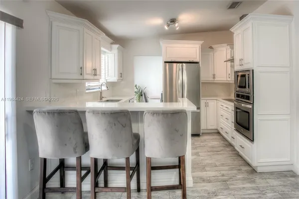 a kitchen with stainless steel appliances granite countertop a dining table chairs refrigerator and sink