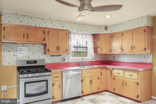 a kitchen with granite countertop a stove a sink dishwasher and white cabinets with wooden floor