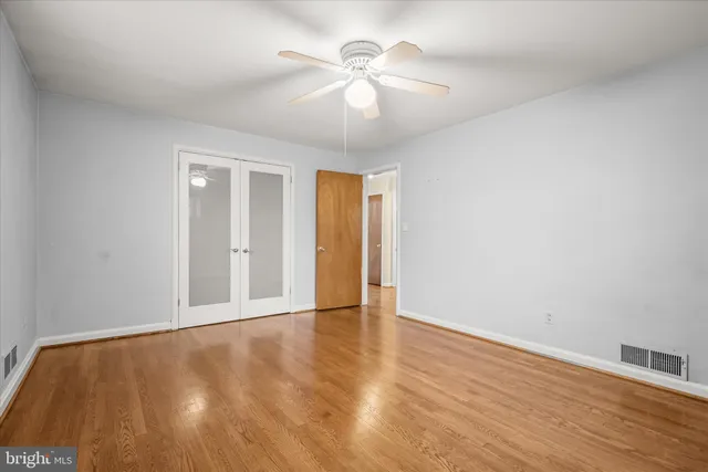 a view of an empty room with window and wooden floor