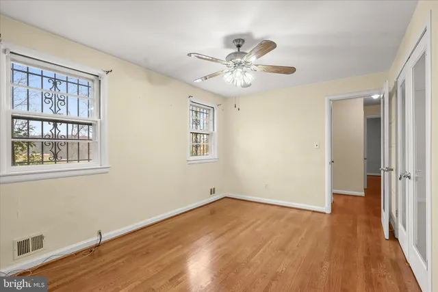 a view of empty room with wooden floor and fan