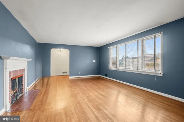 a view of an empty room with window and wooden floor
