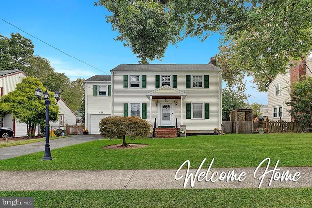 a front view of a house with a garden and trees
