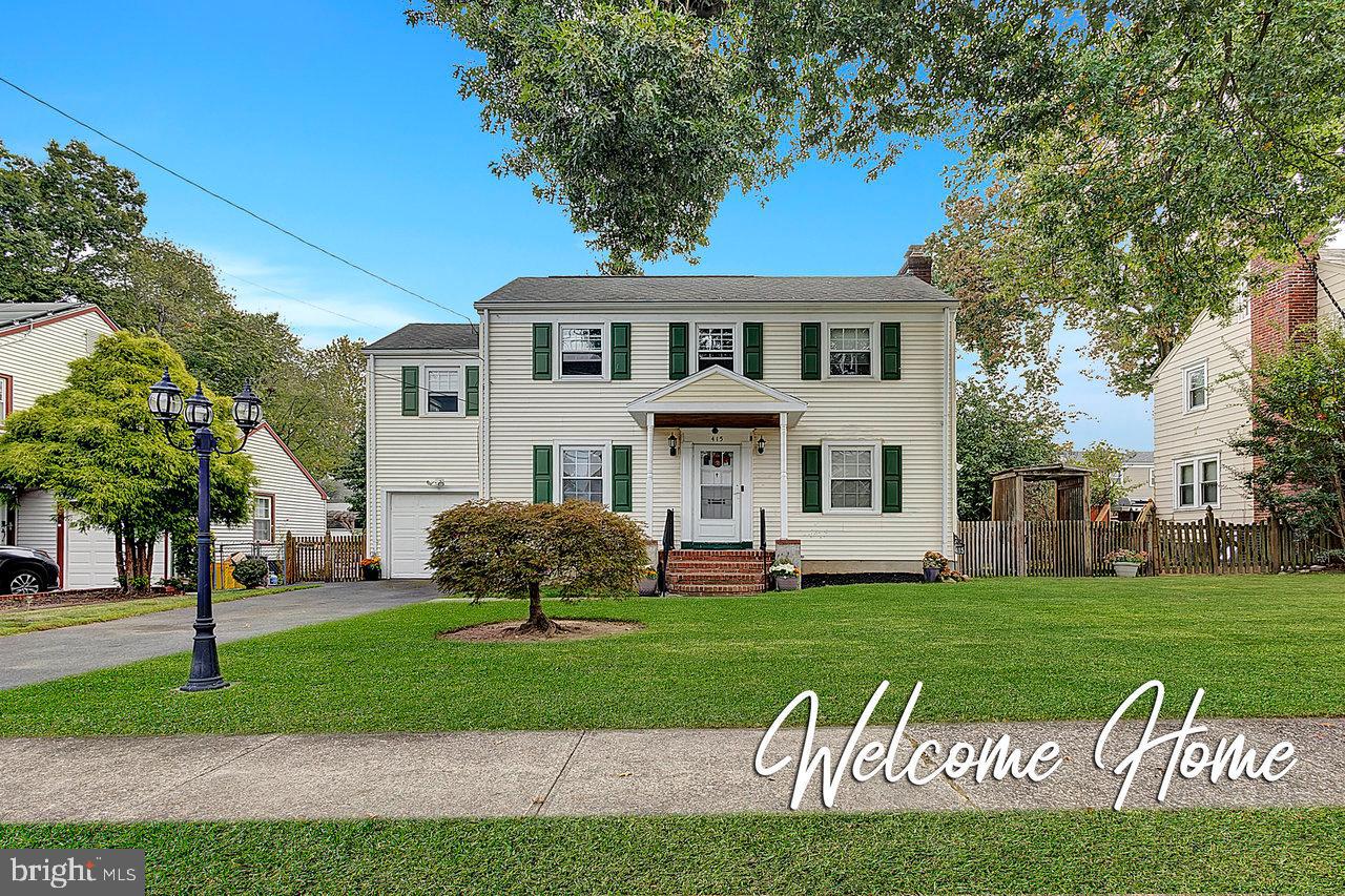 a front view of a house with a garden and trees
