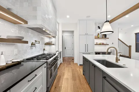 a kitchen with kitchen island stainless steel appliances a sink a stove and a wooden floors