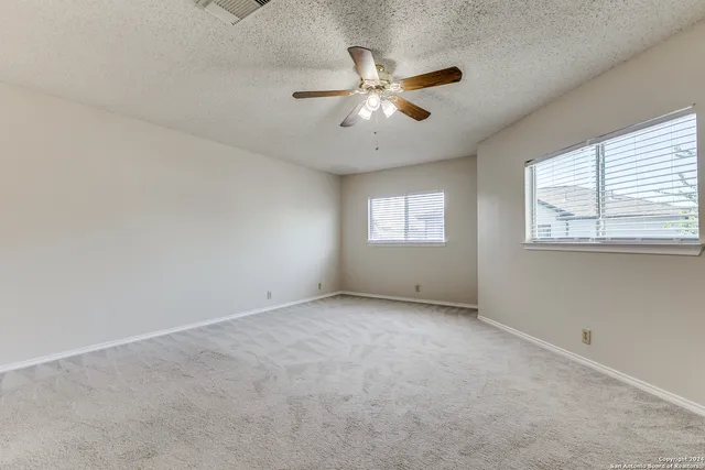 an empty room with windows and fan