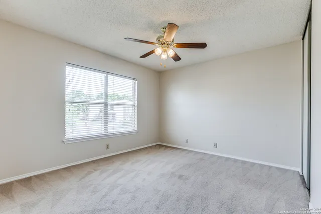 an empty room with a window and a fan