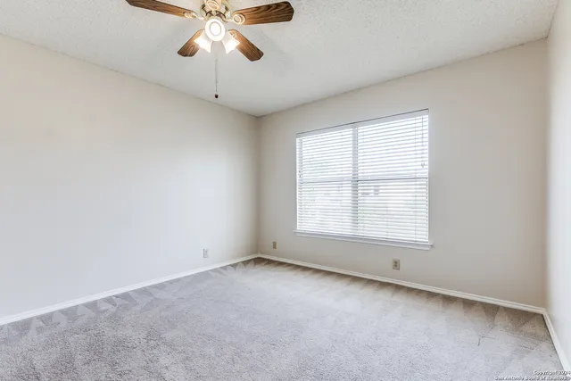 an empty room with a chandelier fan and windows