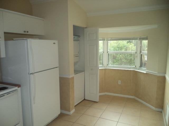 3750 North Jog Road, Unit 203 West Palm Beach, FL 33411 - Photo 5 of 10 a view of an empty room with a refrigerator cabinet and a window