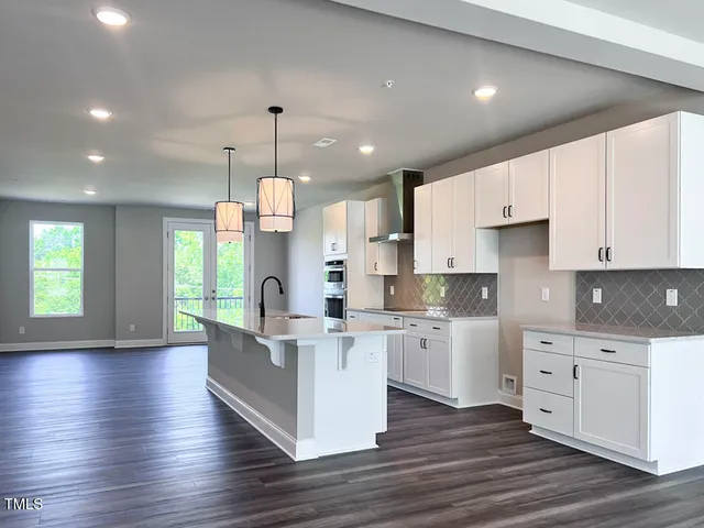a kitchen with kitchen island granite countertop a sink cabinets and wooden floor