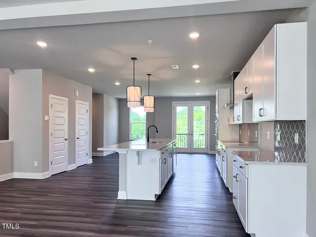 a large kitchen with stainless steel appliances kitchen island a large counter top a sink a refrigerator and a window