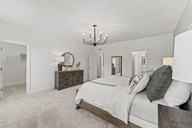 a bedroom with a bed a chandelier and dresser