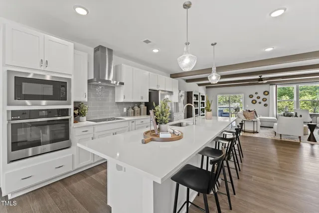 a kitchen with stainless steel appliances granite countertop a stove a microwave a dining table and chairs with wooden floor