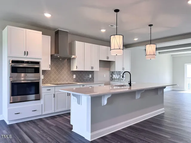 a kitchen with stainless steel appliances granite countertop a sink a stove and a wooden floors