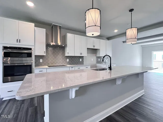 a kitchen with stainless steel appliances granite countertop a sink a stove and a wooden floors