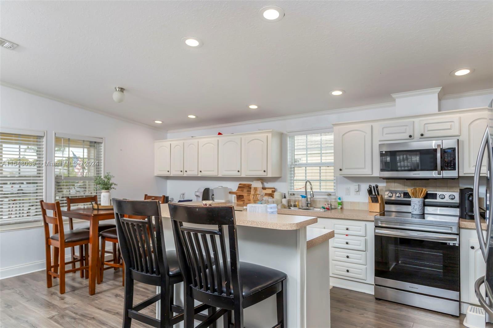 a kitchen with stainless steel appliances kitchen island granite countertop a table chairs microwave and sink