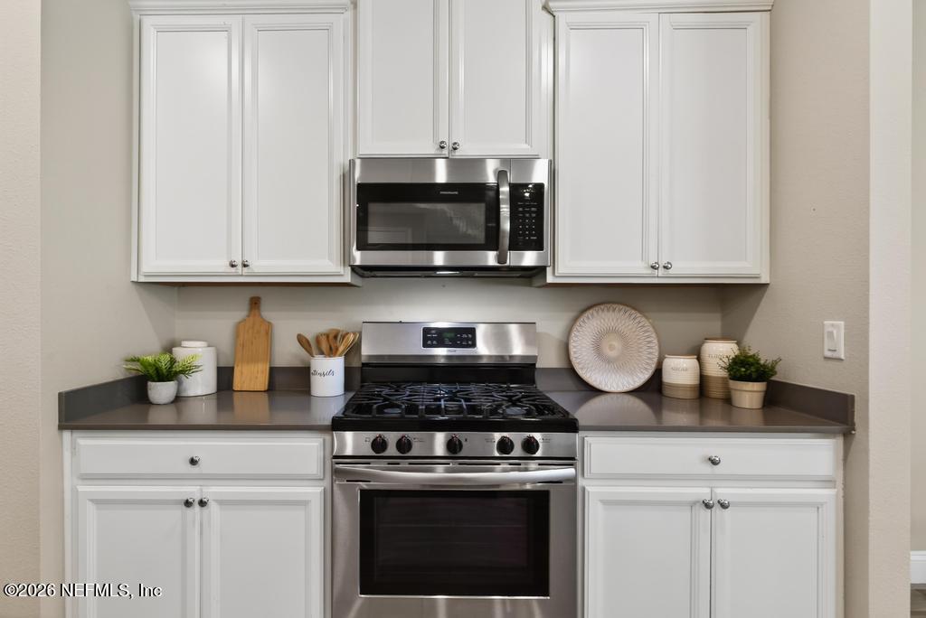 383 Sweet Oak Way St. Augustine, FL 32095 - Photo 15 of 74 a kitchen with granite countertop white cabinets and stainless steel appliances