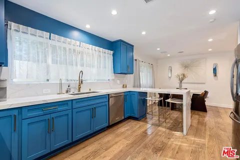 a kitchen with wooden cabinets a sink a stove a dining table and chairs