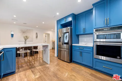 a kitchen with stainless steel appliances granite countertop a refrigerator a stove top oven and cabinets