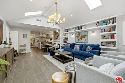 a living room with furniture kitchen view and a chandelier