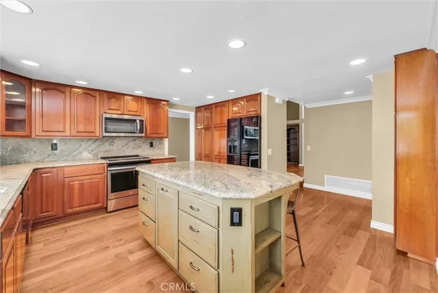 a kitchen with stainless steel appliances granite countertop a stove top oven a sink dishwasher and a refrigerator with wooden floor