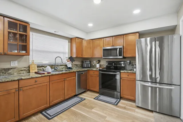 a kitchen with granite countertop a refrigerator stove top oven a sink and dishwasher