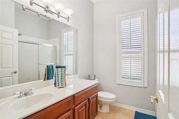 a bathroom with a granite countertop sink toilet a mirror and a window
