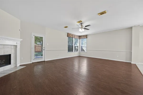 a view of an empty room with wooden floor and a fireplace