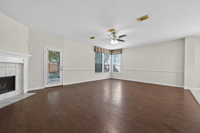 a view of an empty room with wooden floor and a fireplace