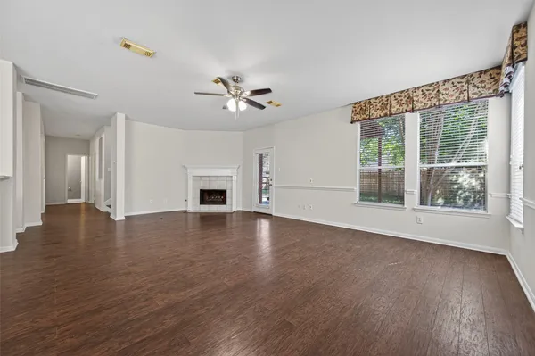 a view of an empty room with a window and wooden floor