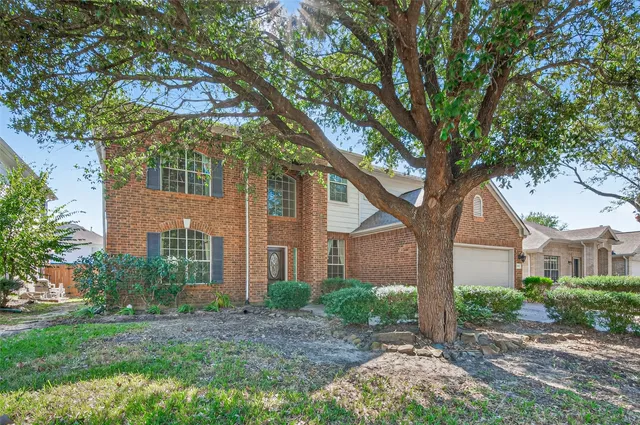 a view of a brick house next to a large trees