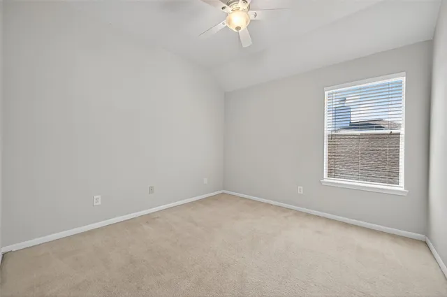 an empty room with a chandelier fan and windows