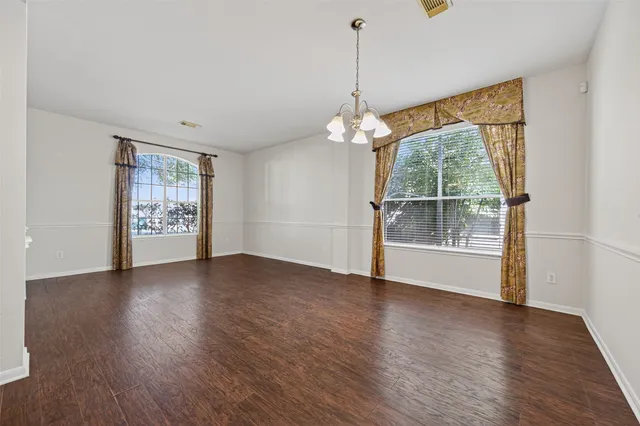 a view of an empty room with a window and wooden floor