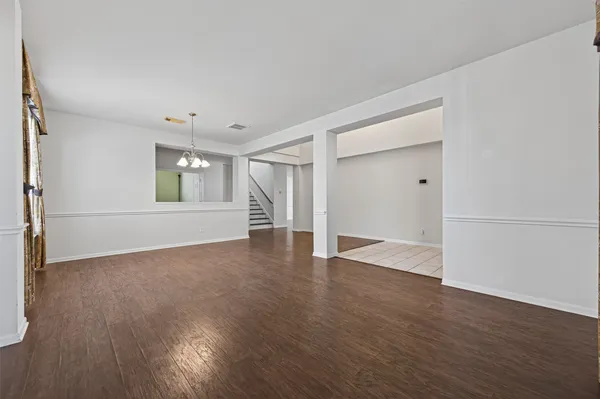 an empty room with wooden floor cabinet and windows
