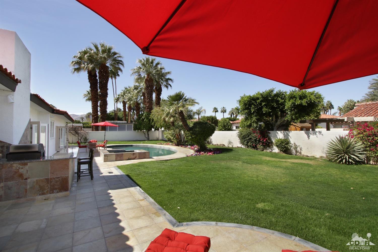 75570 Fairway Drive Indian Wells, CA 92210 - Photo 32 of 38 a backyard of a house with table and chairs under an umbrella