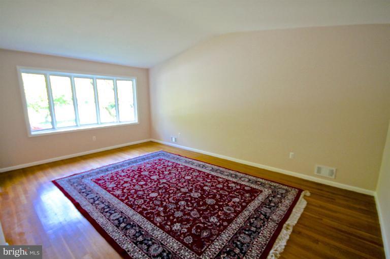 13007 Middlevale Lane Silver Spring, MD 20906 - Photo 14 of 30 an empty room with wooden floor and a rug