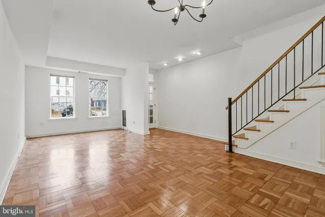 a view of an empty room with stairs and chandelier fan