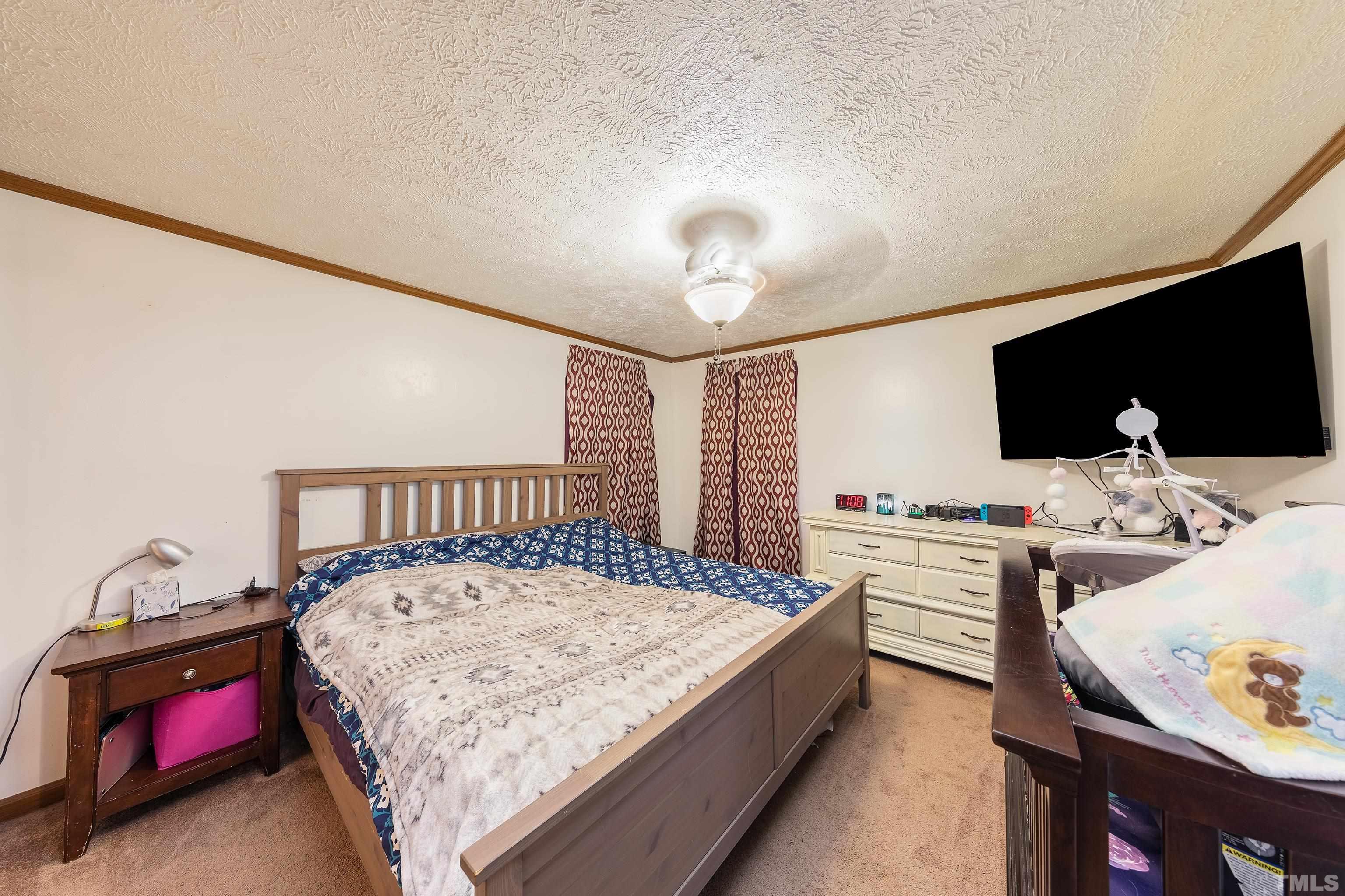 1469 Semora Road Roxboro, NC 27574 - Photo 12 of 22 a bed sitting in a bedroom next to a window with a flat screen tv