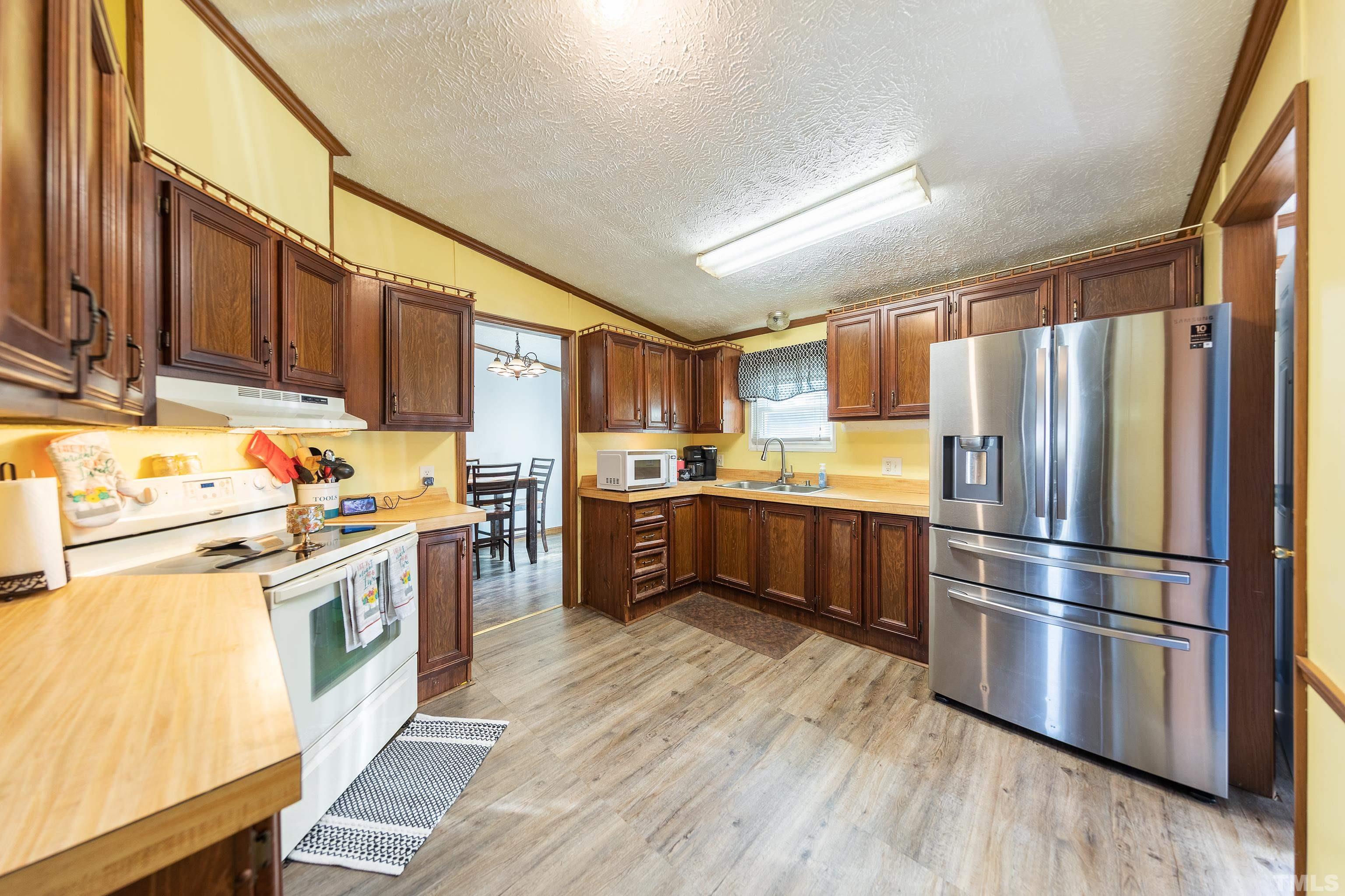 1469 Semora Road Roxboro, NC 27574 - Photo 10 of 22 a kitchen with stainless steel appliances wooden floor sink and wooden cabinets